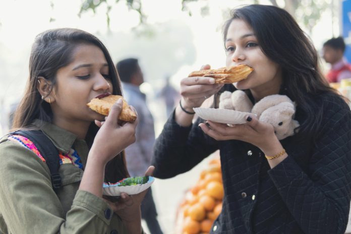 Girls eating street food with enjoying. street